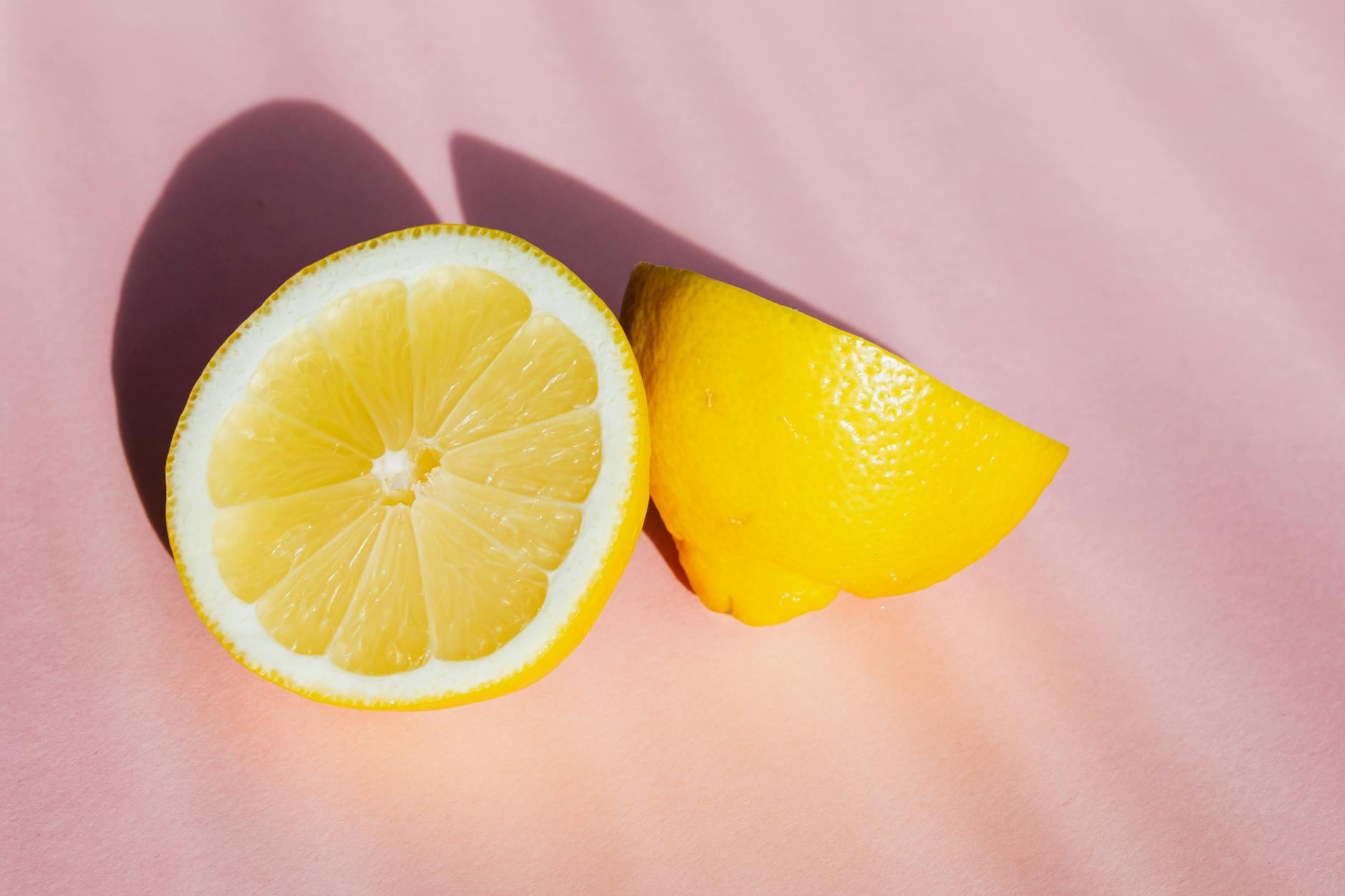 Fresh lemons on a pink background in sunlight, symbolizing brightness and renewal