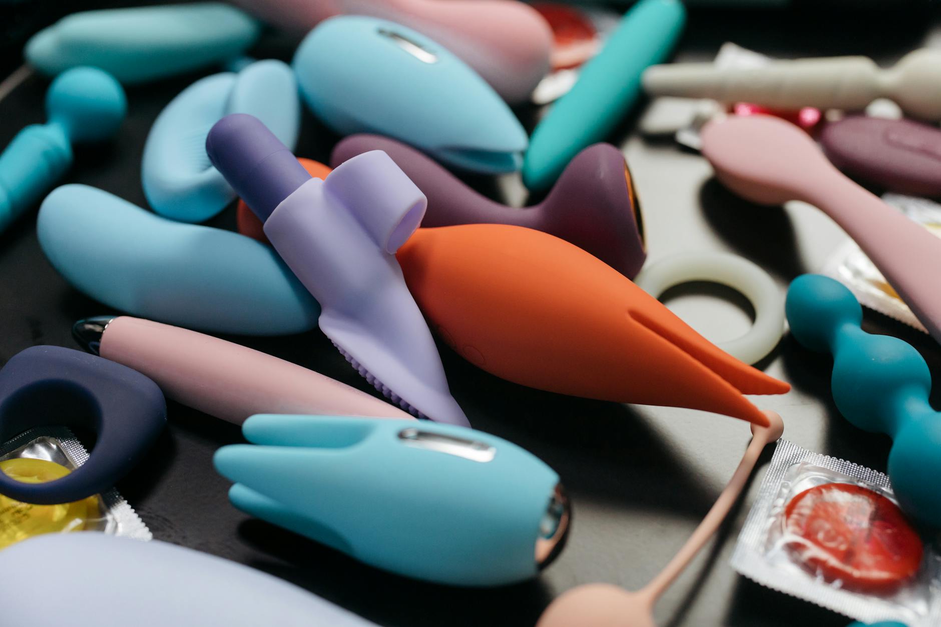 Hand holding an orange vibrator against a minimalistic purple backdrop, showcasing modern sensuality and solo pleasure