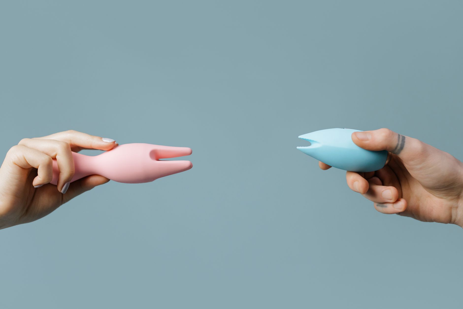 A blue silicone clitoral vibrator held in hand against a purple background, symbolizing the restart of self-pleasure and intimacy.