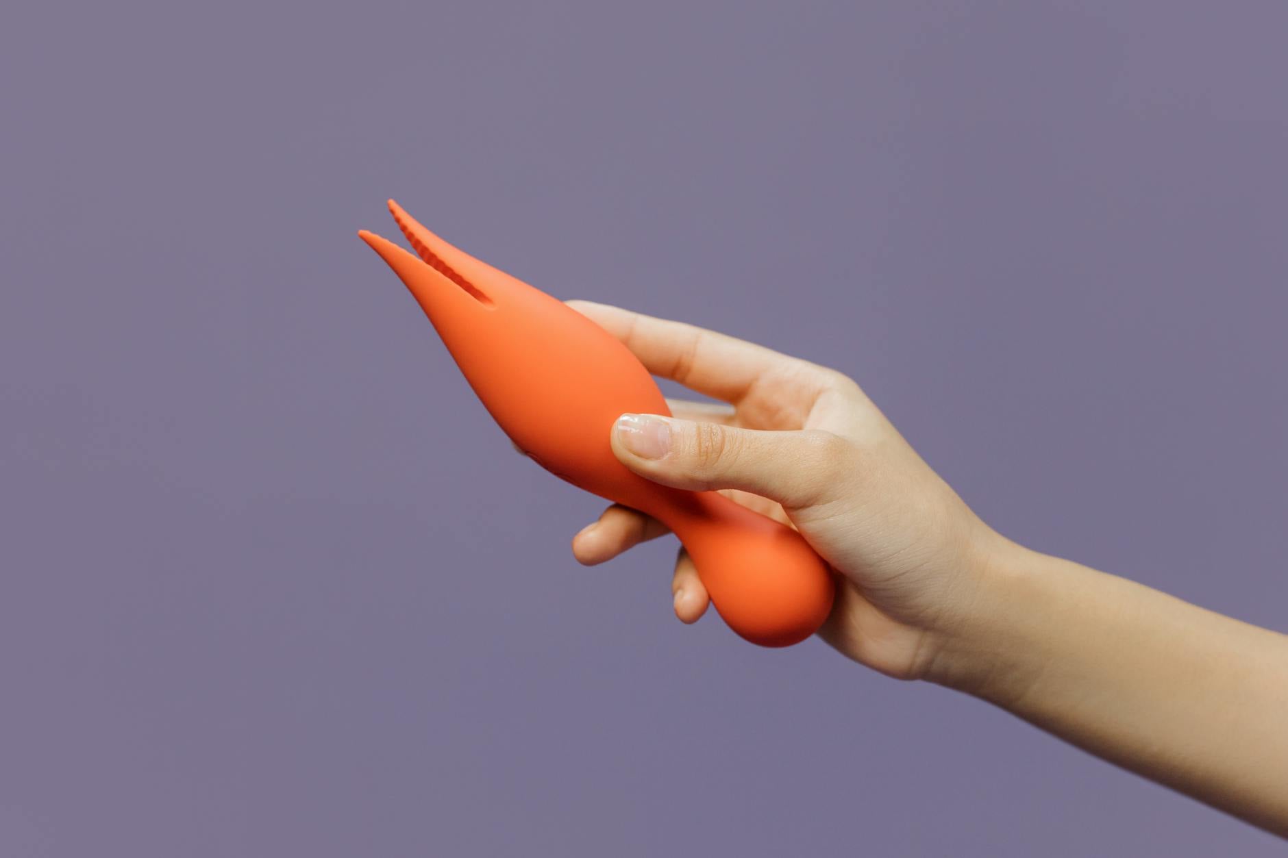 Close-up of hands holding a sleek blue vibrator against a purple background