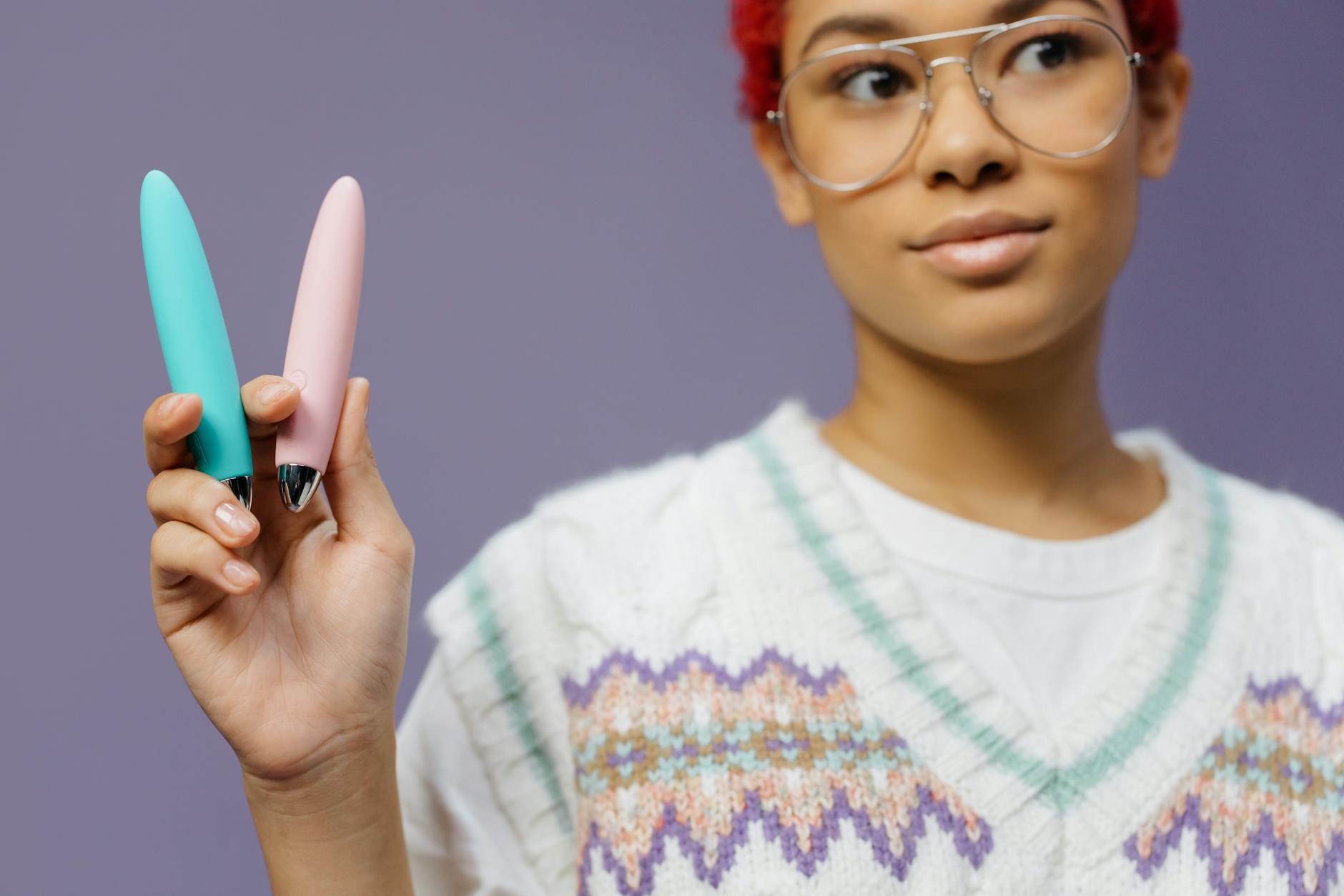 Woman holding two colorful vibrators, representing multiple partners and varying pleasure needs.
